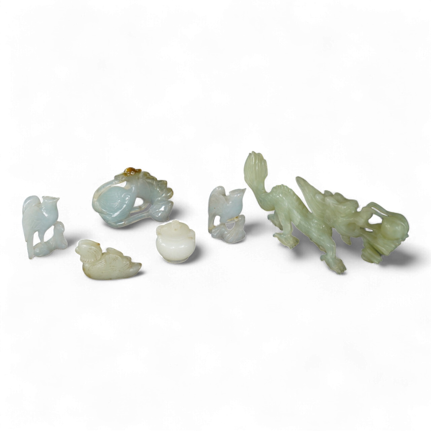 A Chinese jade figure of a Mandarin duck and a miniature pot and cover, three jadeite carvings and a bowenite dragon, 16.5cm